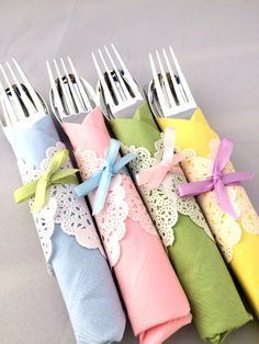 four forks are wrapped in napkins and tied with ribbons on the ends, sitting next to each other