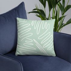 a green pillow sitting on top of a blue couch next to a potted plant