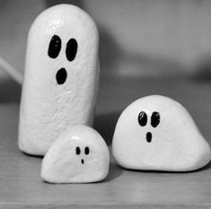 three white rocks with faces painted on them