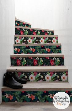 a pair of black shoes sitting on top of a set of stairs with floral designs