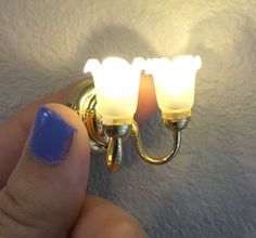 a person with blue nail polish holding two lights