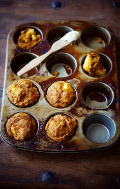 a muffin tin filled with cupcakes on top of a wooden table