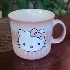 a pink hello kitty coffee cup sitting on top of a wooden table