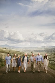 a group of people walking down a dirt road in the middle of an open field