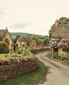 an old country road with stone buildings and flowers growing on the side of each building