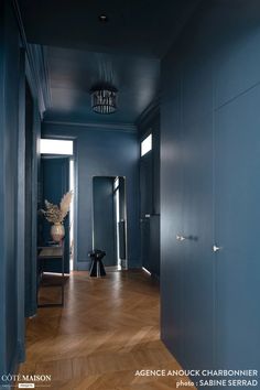 an empty hallway with blue walls and wooden floors