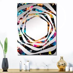 a mirror sitting on top of a wooden table next to vases and plants in front of a white wall