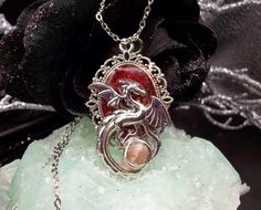 This dragon protection necklace contains dragon's blood resin, chili powder, red pepper flakes, tarragon, and ashes covered with fine red glitter and sealed with resin. The dragon holds a sunstone with its tail. The necklace chain is 2mm wide & 18 inches long. Items may vary slightly mostly in regards to the shape of the sunstone. Nickel-free Fantasy Necklaces For Gifts, Necklace Dragon, Protection Amulet, Dragon Necklace, Dragon Jewelry, Protection Necklace, Herbal Blends, Dragons Blood, Dragon Pendant