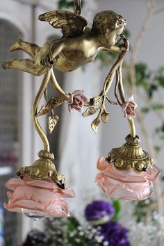 an angel figurine hanging from a chandelier with pink and gold flowers