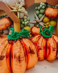 three shiny orange pumpkins with green numbers on them sitting in front of some decorations