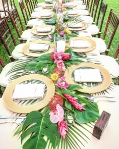 a long table set with plates and place settings for an outdoor dinner party in the grass