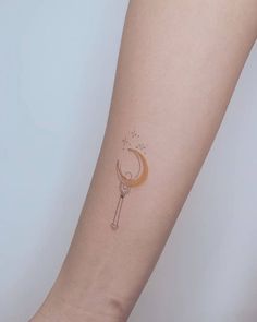 a tattoo on the arm of a woman with a crescent moon and key in it