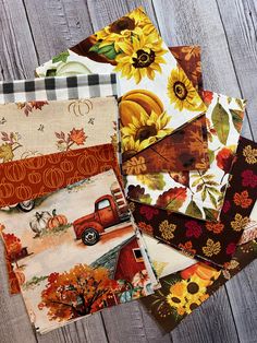 several different types of fabric are laid out on a wooden surface, including sunflowers and pumpkins