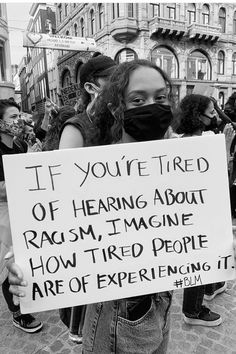 a woman holding a sign that says if you're tired of hearing about racism, i'm imagine how tired people are of experiencing