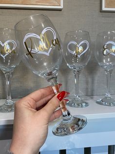 a hand holding a wine glass with the word love written on it in gold lettering