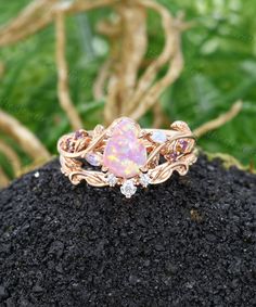 an opal and diamond ring sitting on top of a rock