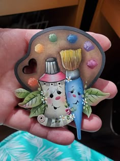 a hand holding a small ceramic decoration with two toothbrushes