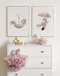 two pictures hang on the wall above a dresser with pink flowers and stuffed animals in it