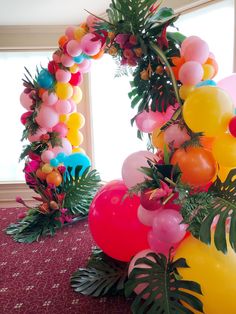 balloons, palm leaves and other decorations are on the floor in front of a window