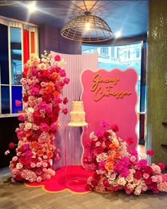 a wedding cake and flowers on display in front of a sign