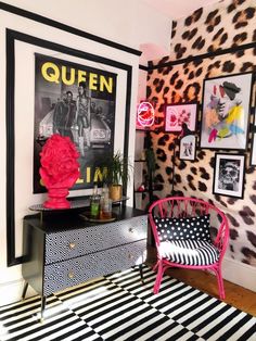 a black and white striped rug in a room with pink accents on the wall, an animal print chair next to a dresser