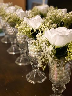 there are many vases with white flowers in them on the table, along with pearls