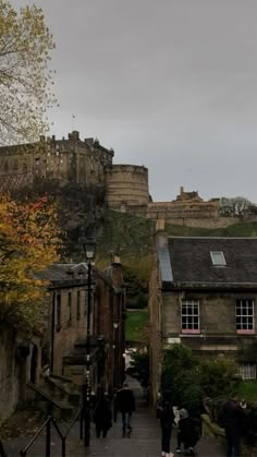 people are walking up and down the stairs in front of some castle like buildings on a hill