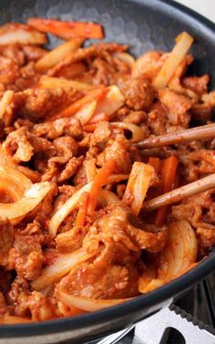 a pan filled with meat and onions cooking on top of an open stovetop burner