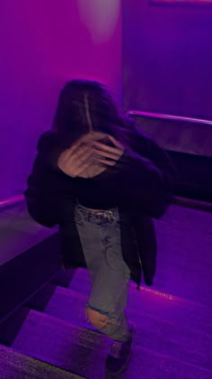 a person walking up some stairs with their back to the camera and purple light behind them