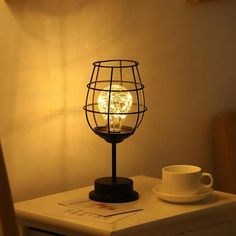 a light bulb sitting on top of a table next to a cup and saucer