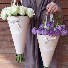 a man holding two vases with flowers in them and one has a purple robe on