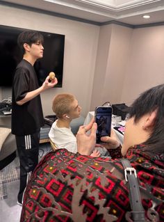 a man taking a photo with his cell phone while two other men watch