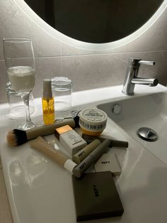 a bathroom sink with various personal care items sitting on top of it next to a mirror