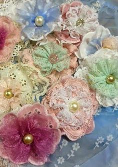 several different colored flowers on a lace doily with pearls in the center and beads at the bottom