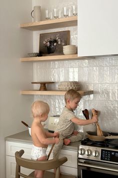 two young children are playing in the kitchen