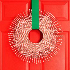 a red door with a green ribbon hanging from it's side and a wreath made out of pins