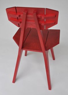 a red chair sitting on top of a white floor next to a wooden table with two legs