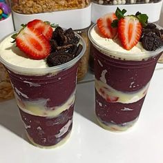 two dessert cups with strawberries and oreo cookies on the top one is purple