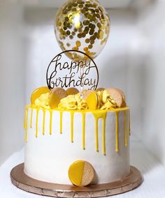 a birthday cake decorated with gold confetti and a happy birthday balloon on top