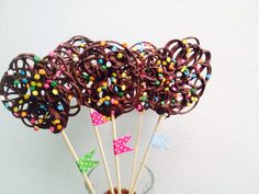 chocolate lollipops with sprinkles on sticks in a glass vase