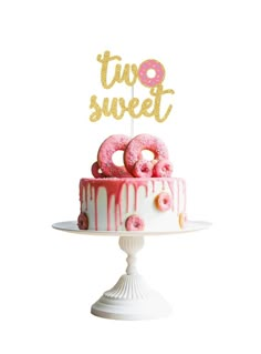 a white cake with pink frosting and donuts on top that says two sweet