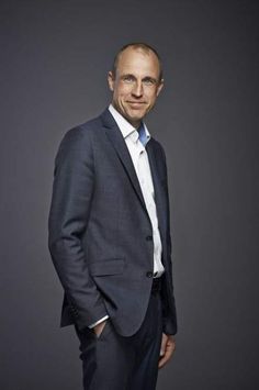 a man in a suit and tie posing for a photo with his hands in his pockets