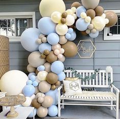 a bunch of balloons that are on the side of a house with a bench in front of it