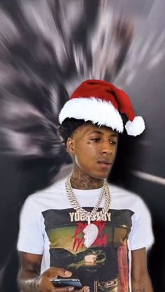 a young man wearing a santa hat and holding a cell phone in his hand while looking at the camera