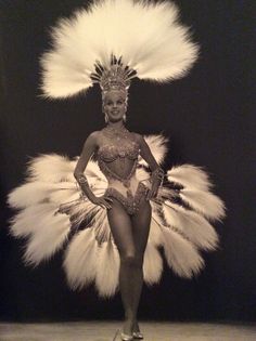 a black and white photo of a woman in a costume with feathers on her head