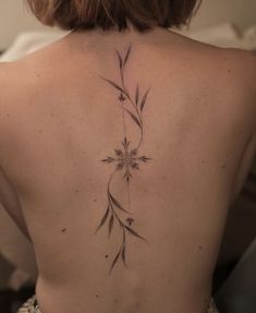 the back of a woman's upper body with flowers on her left shoulder and behind her is a vine