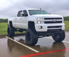 a white truck parked in a parking lot on a rainy day with the hood up