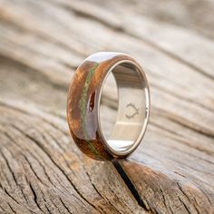 a wooden ring with green and brown wood inlays on the outside of it