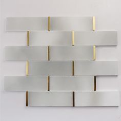 a white and gold tile wall with some lines on the back ground, one line is parallel to the other