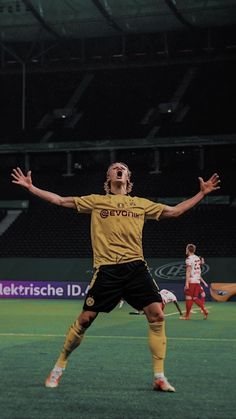 a man standing on top of a soccer field with his arms outstretched in the air